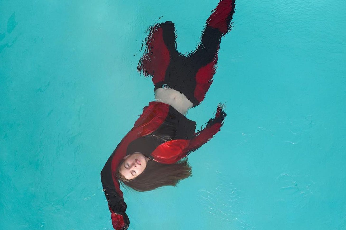 Hannah Lee Jade floats in a swimming pool wearing black and red threads.